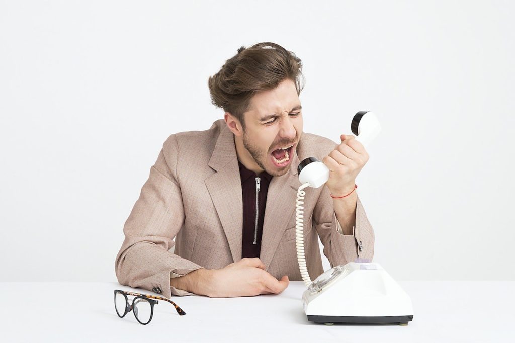 Image shows angry man on the phone - articles discusses the pitfals of scam holidays and how to avoid them