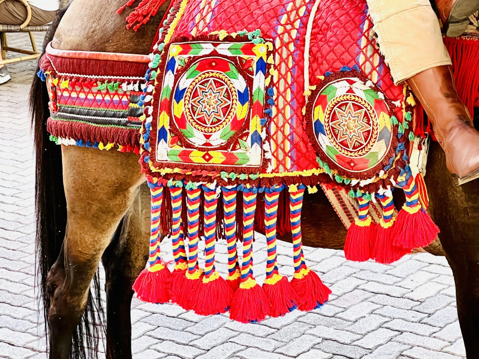 The image shows the vibrant colours of the traditional dress adorning the horses at the Competa Summer Feria.